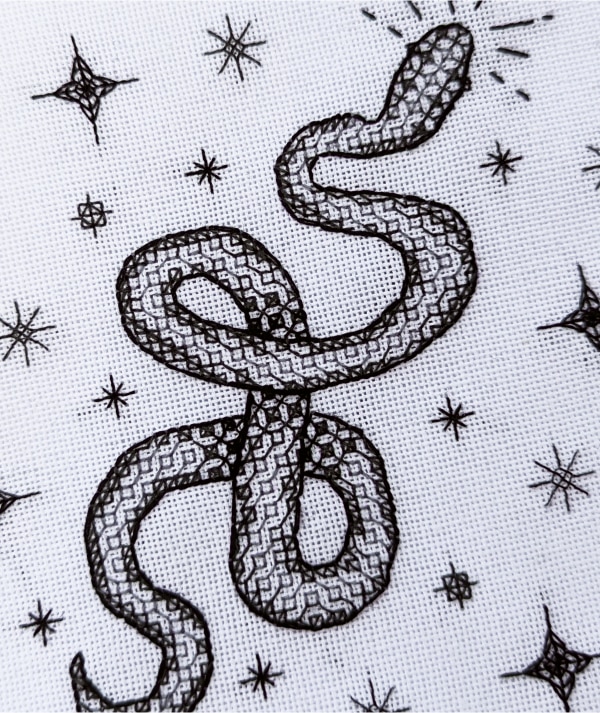 Close up of a stitched snake surrounded by stars blackwork pattern